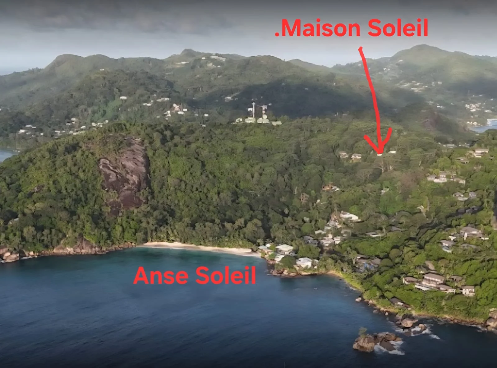 Aerial view of Anse Soleil bay with Maison Soleil marked on the forested hillside above the beach — drone perspective at Maison Soleil, Anse Soleil, Seychelles