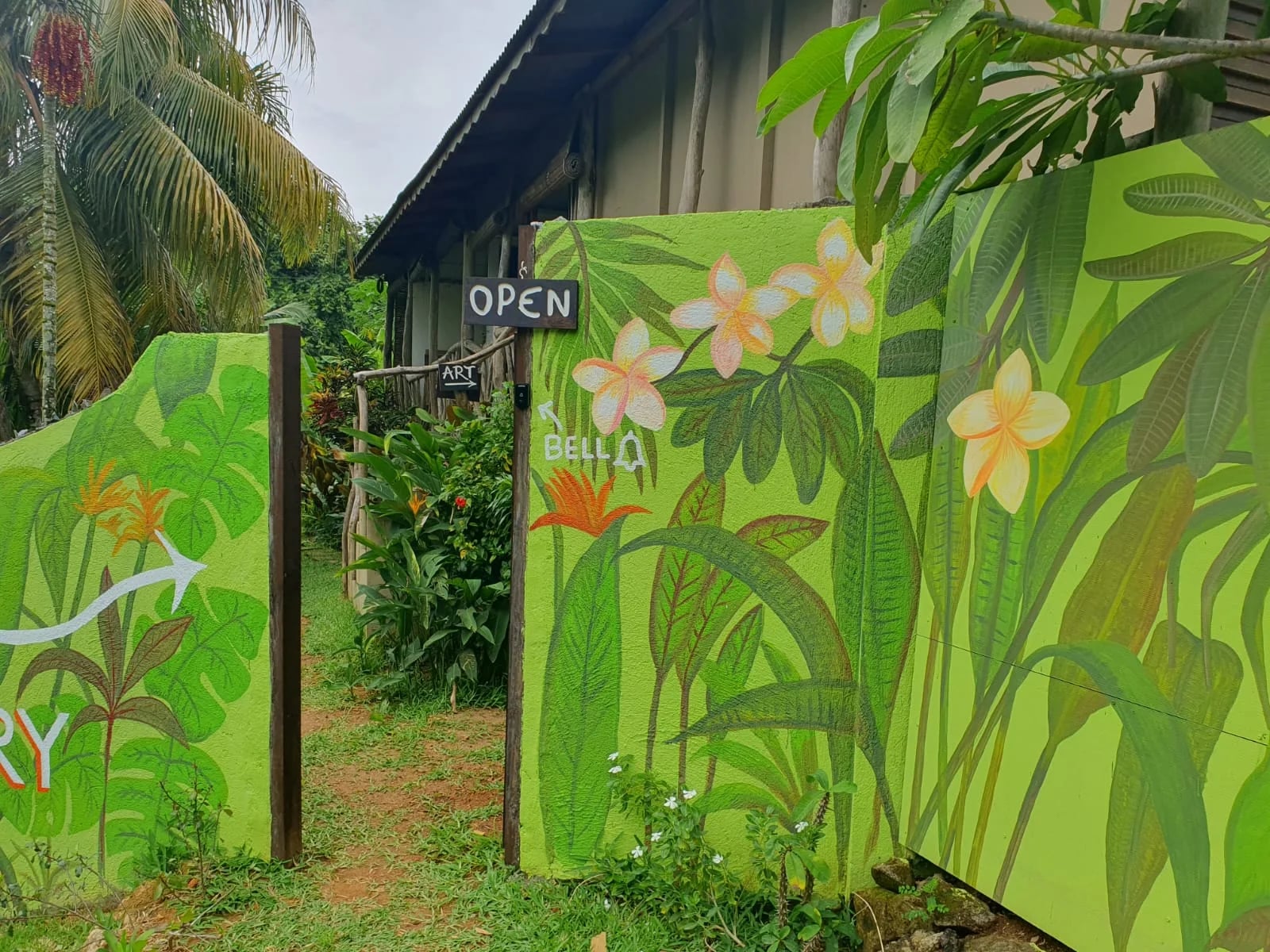 Hand-painted art gallery entrance mural with frangipani flowers, OPEN sign and garden path — Andrew Gee Art Gallery at Maison Soleil at Maison Soleil, Anse Soleil, Seychelles
