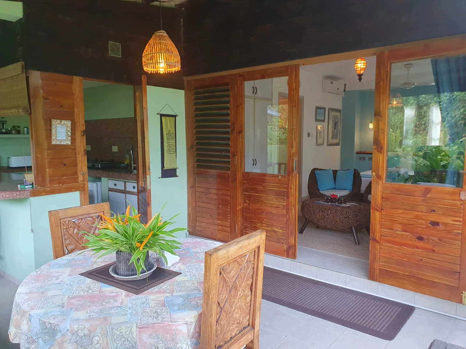 Private covered terrace with carved wooden dining set and bird-of-paradise flowers — Garden Suite 1 at Maison Soleil, Anse Soleil, Seychelles
