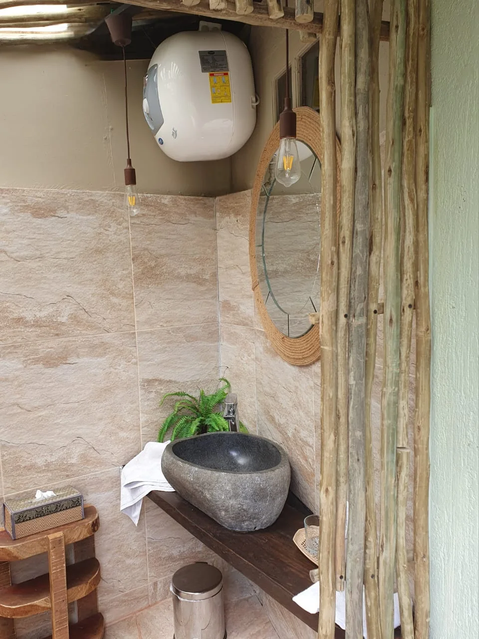 Bathroom vanity with natural stone basin, rope-framed circular mirror and Edison pendant lights — Garden Suite 2 ensuite at Maison Soleil, Anse Soleil, Seychelles
