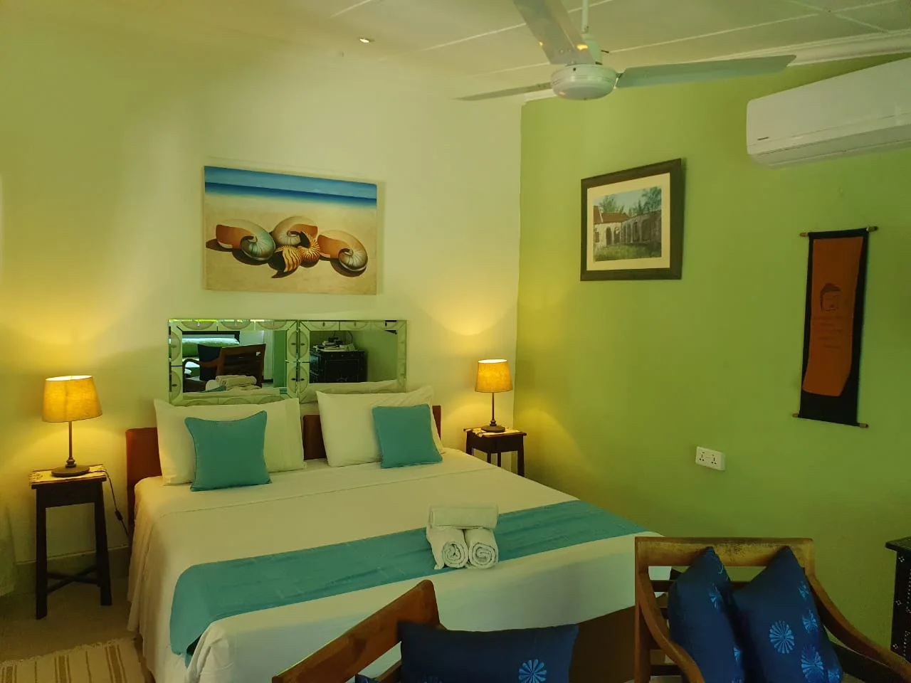 Bedroom with turquoise runner, lime-green accent wall, flat-screen TV and tropical seashell painting — Garden Suite 3 boutique accommodation at Maison Soleil, Anse Soleil, Seychelles