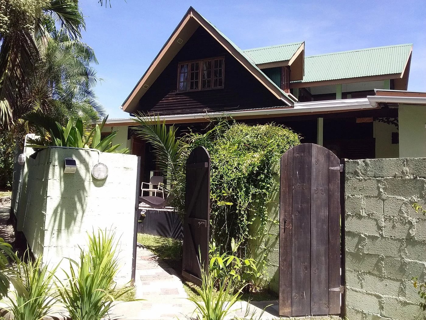 Private arched wooden entrance gate to Maison Soleil — tropical garden path at Maison Soleil, Anse Soleil, Seychelles