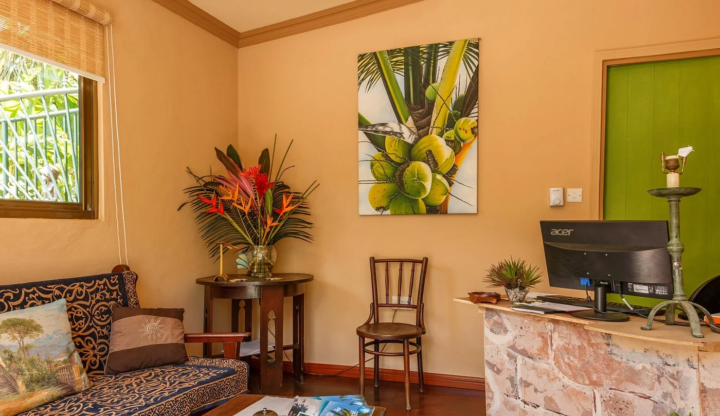 Maison Soleil reception interior with heliconia flowers and palm artwork — welcome desk at Maison Soleil, Anse Soleil, Seychelles