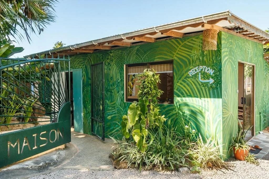 Exterior reception wall painted with layered palm fronds and RECEPTION sign — property entrance at Maison Soleil, Anse Soleil, Seychelles