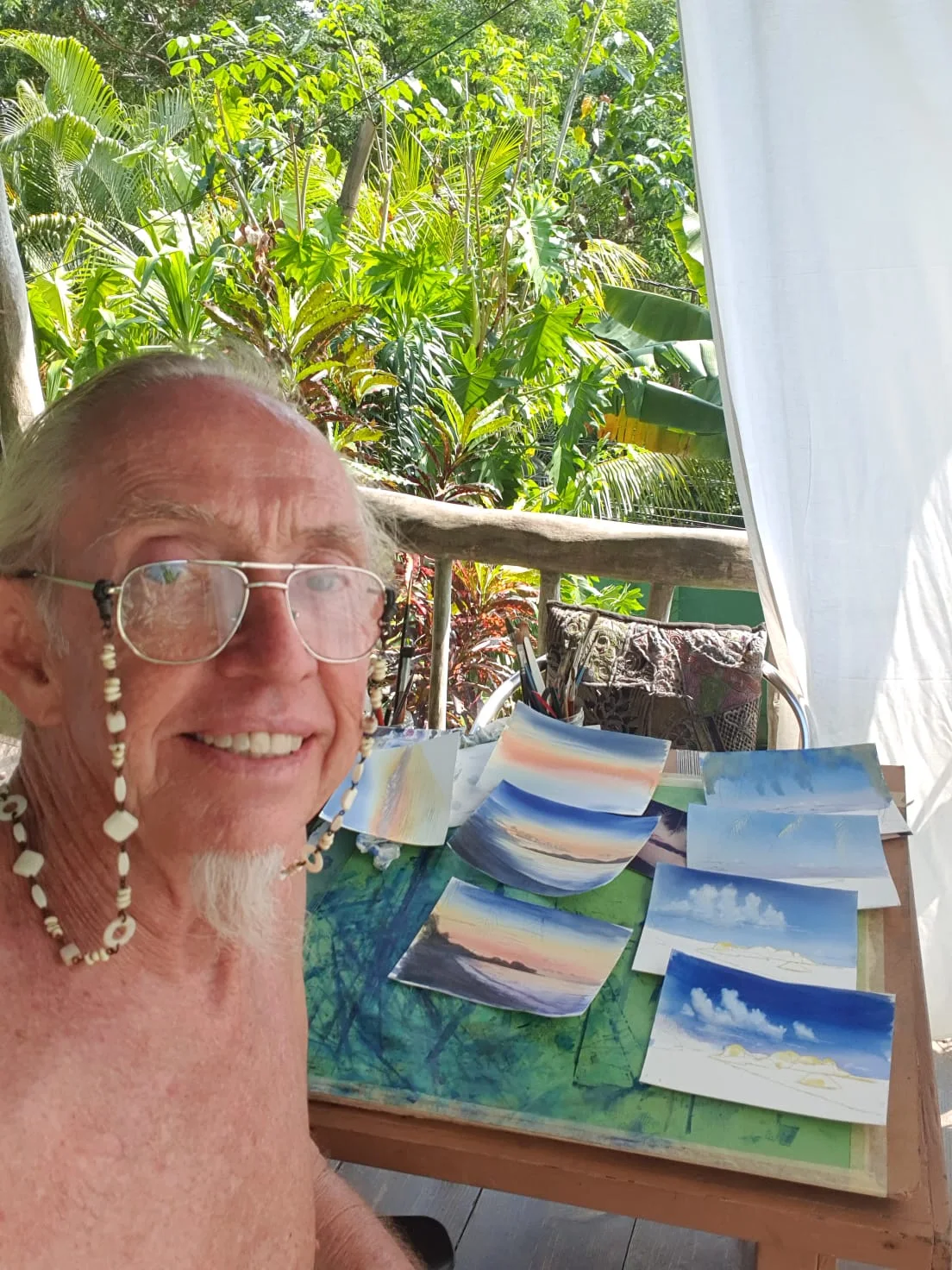 Artist Andrew Gee with his Seychelles watercolour paintings on a tropical balcony — owner of Maison Soleil at Maison Soleil, Anse Soleil, Seychelles