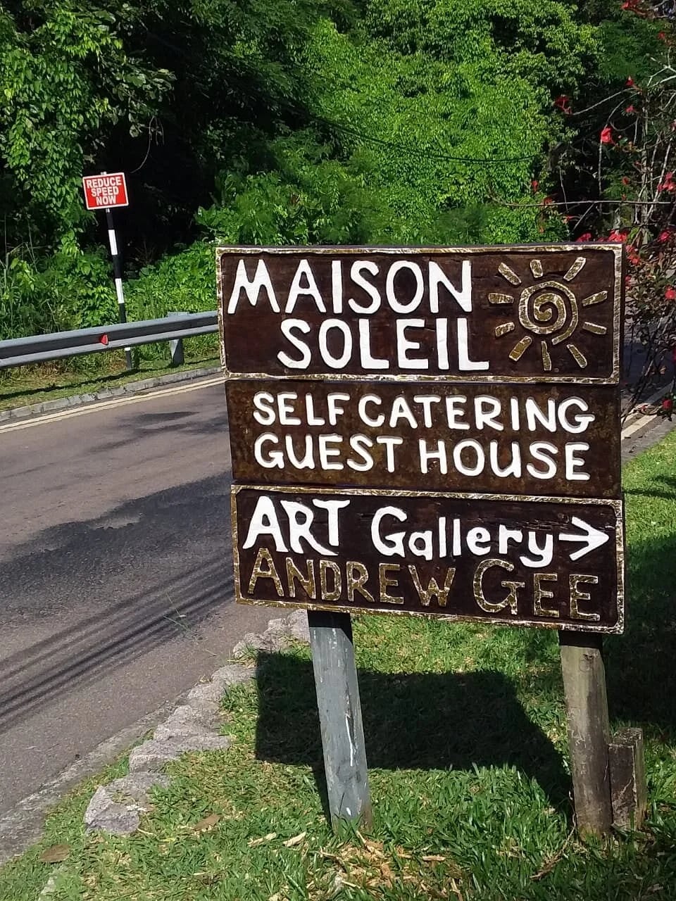 Hand-painted wooden road sign for Maison Soleil and Andrew Gee Art Gallery — directions on Anse Soleil Road at Maison Soleil, Anse Soleil, Seychelles